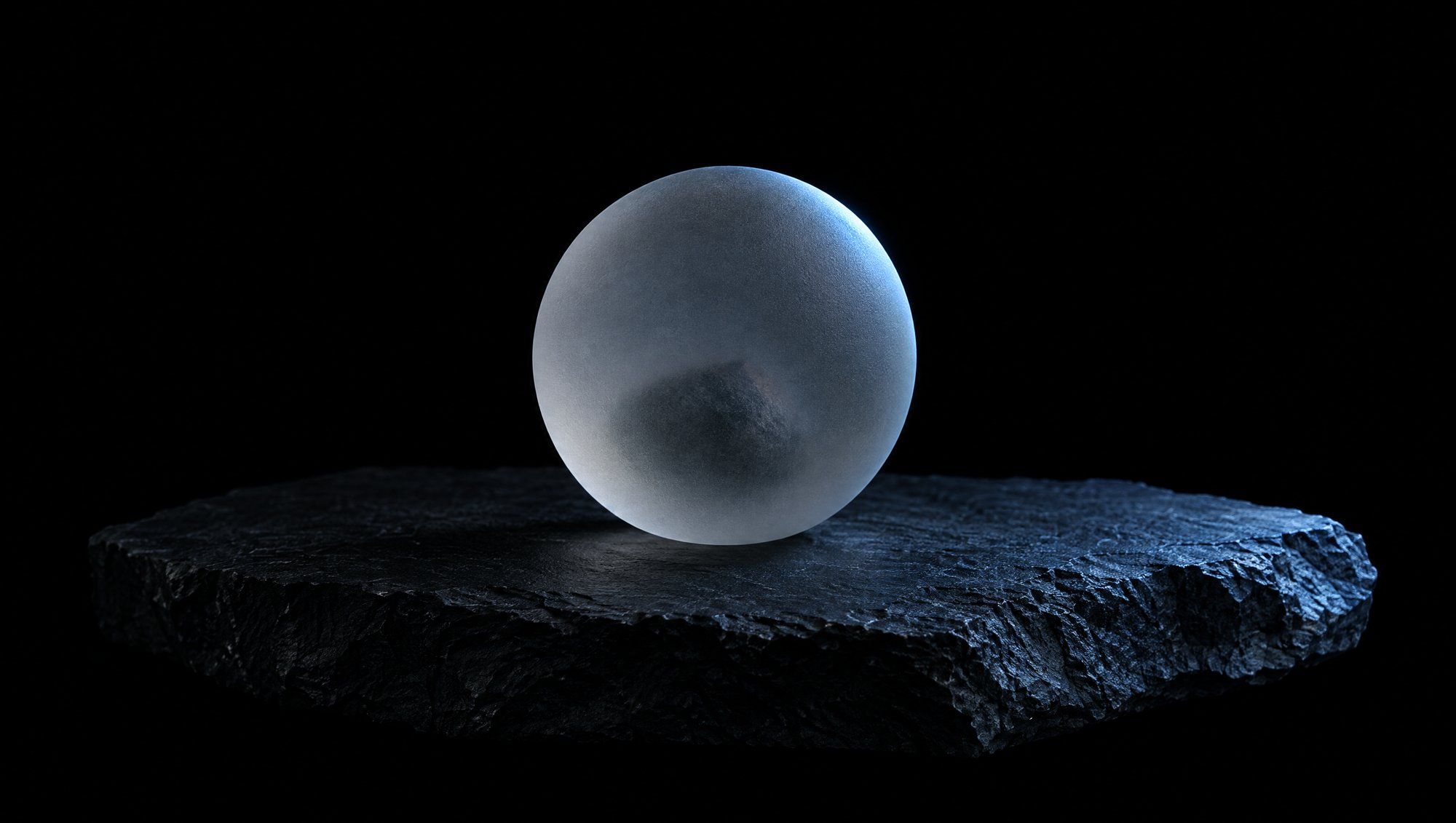 A frosted glass sphere resting on a rough dark slate slab against a black background, the blurred shape of a small stone visible inside it, its edge lit by a cool slate-blue light.