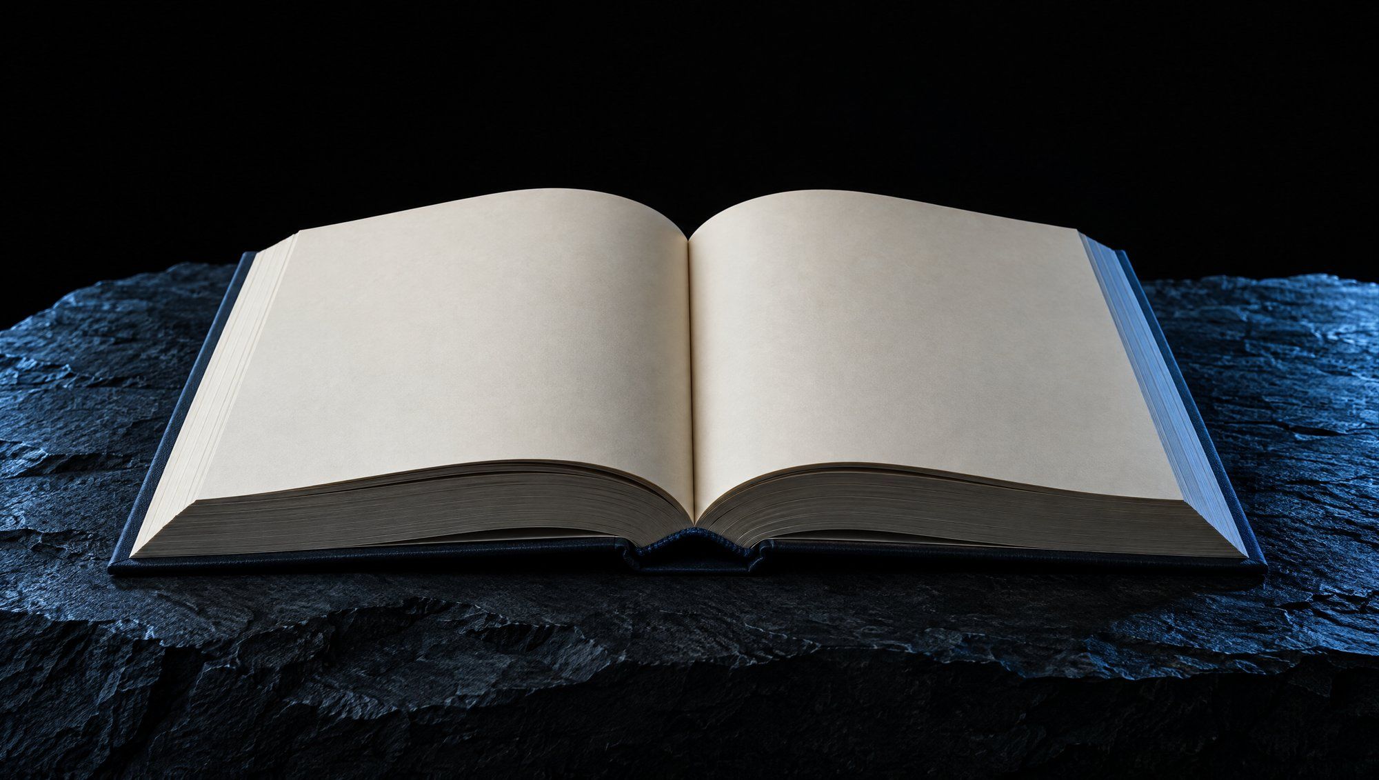 A thick open hardcover book with blank cream pages lying on rough dark slate stone against black, its page edges and the stone lit by cool slate-blue light.
